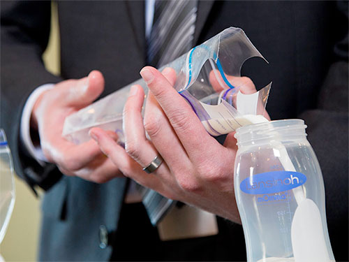 Dad pouring breastmilk into feeding bottle from the storage bags